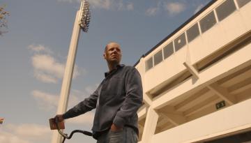 Person står med cykel utanför fotbollsstadion