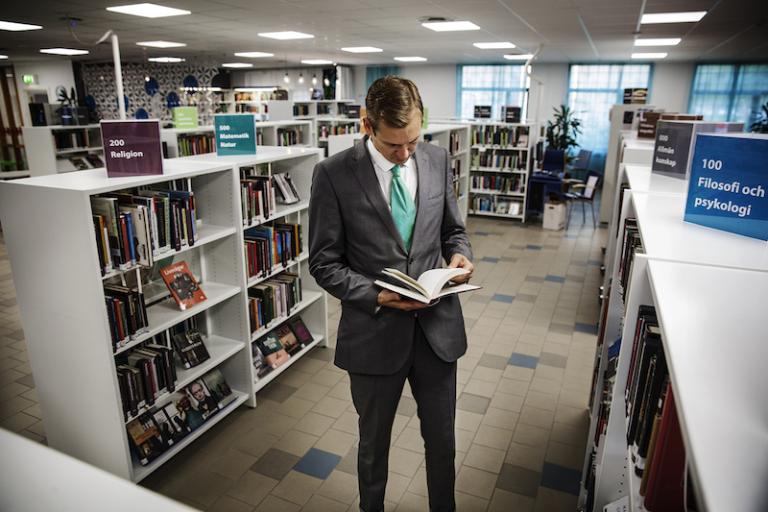 Henrik Svalander läser en bok inne på ett bibliotek