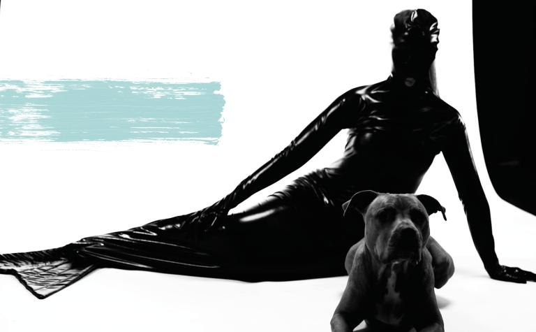 Kvinna i svart latexdräkt poserar med hund