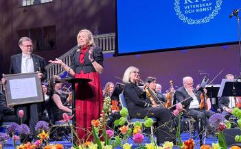 Prisutdelning på en scen. Två personer på förscenen. Orkester i bakgrunden.