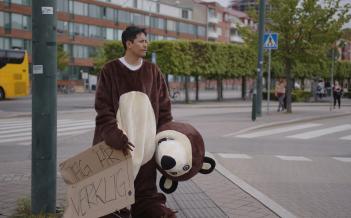 Man i nallebjörnskostym står vid Södervärns bussstation